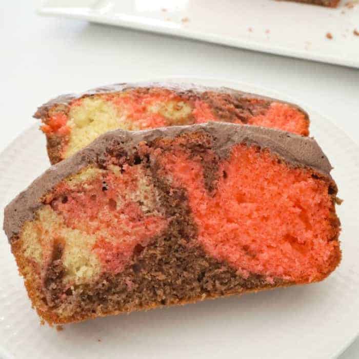 Two slices of marble cake with chocolate frosting, with swirls of vanilla, strawberry and chocolate cake texture.