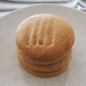 A white speckled plate with 4 ginger biscuits on top of one another.