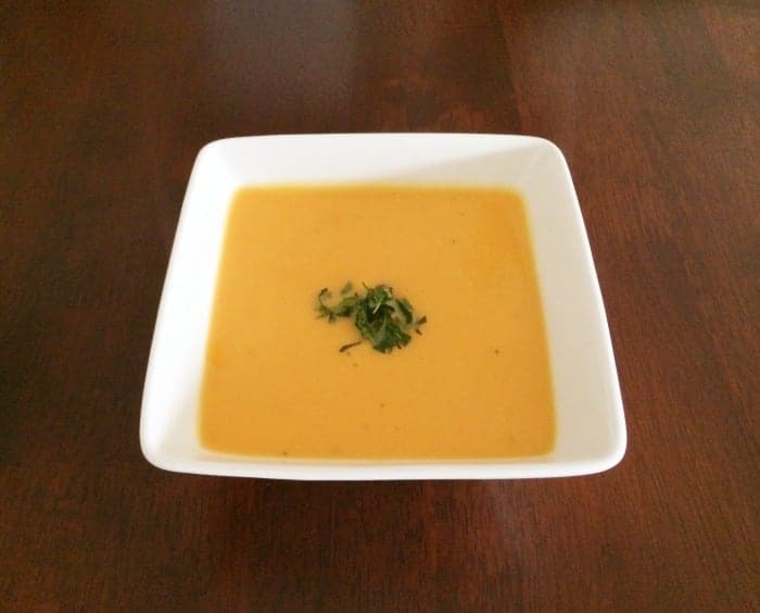 Sweet potato soup in a square white bowl, with chopped coriander on top.