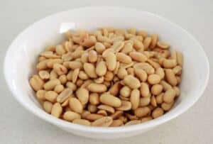 Shelled peanuts in a white bowl.