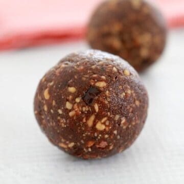 Two healthy bliss balls made with almonds, dates and cacao.