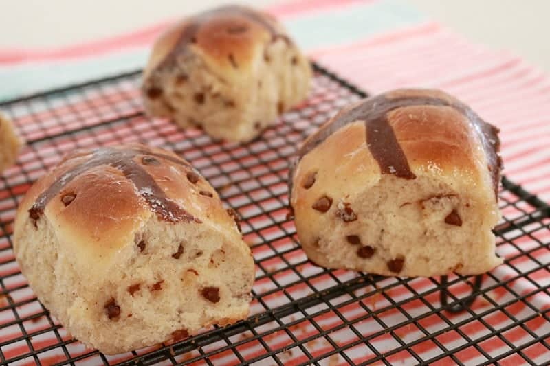 Chocolate chip Hot Cross Buns resting on a wire cooling tray.
