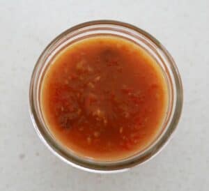 An overhead shot of a glass bowl filled with tomato chutney.
