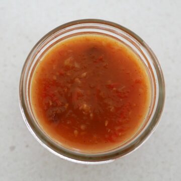 An overhead shot of a glass bowl filled with tomato chutney.