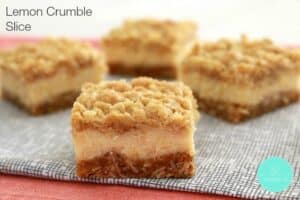 Squares of lemon crumble slice with a creamy lemon layer over the base and crunchy crumble on top.