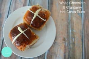 Two Hot Cross Buns made with chocolate and cranberries, served on a plate.