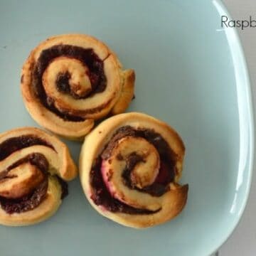 Raspberries and Nutella rolled through baked scrolls served on a plate.