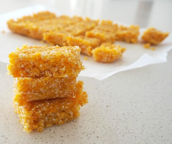 Squares of slice made with apricot and coconut on a bench. 