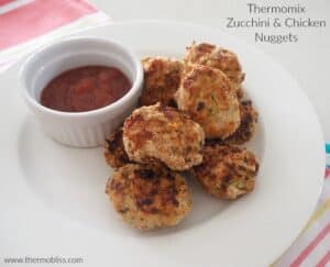 A small bowl of relish next to a pile of golden crunchy nuggets made with chicken and zucchini.