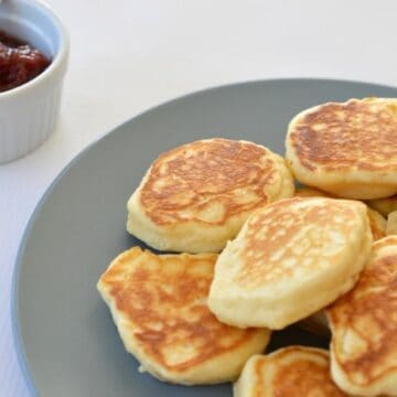 A plate with a pile of golden pikelets on it.