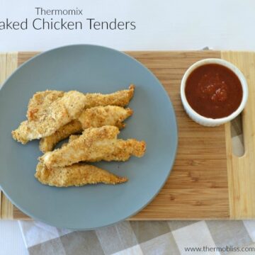 Crumbed golden chicken tenders on a plate with a bowl of tomato sauce beside.