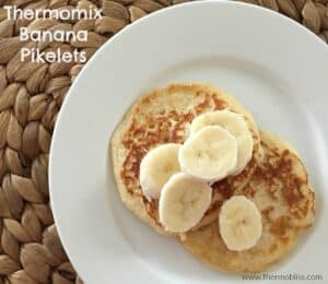 Banana pikelets on a plate with sliced banana on top.