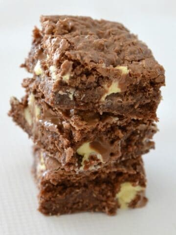 A stack of three pieces of a chocolate slice with chunks of white chocolate inside.