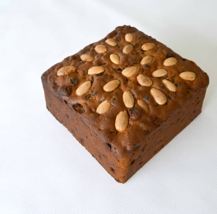 A square Christmas fruit cake with blanched almonds baked on top
