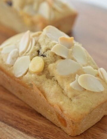A close up of a mini loaf baked with white chocolate and cranberries, with flaked almonds on top.