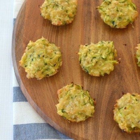 An overhead shot of a wooden board with mini muffins made with zucchini and cheese on it.