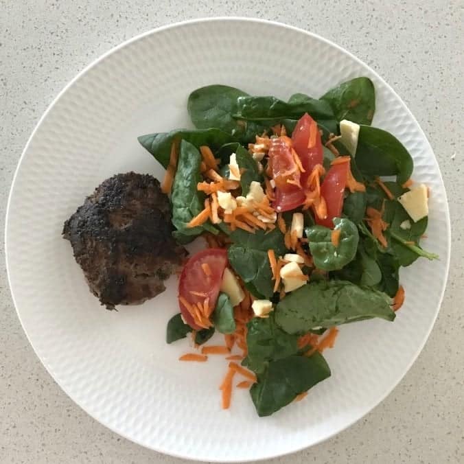 A simple Thermomix Mince Recipe, a beef rissole and salad sitting on a white plate. 