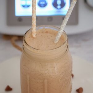A jar with two straws in it, filled with a creamy chocolate drink.