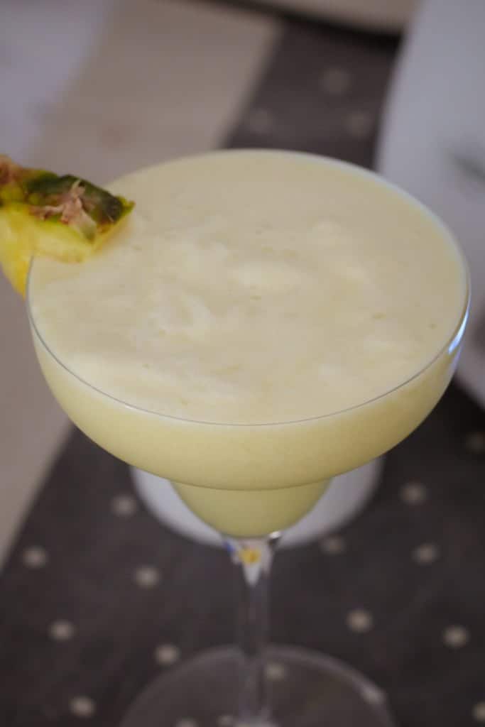 Pineapple garnishing a creamy cocktail filled glass.