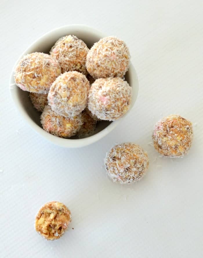 Round truffle balls made with clinkers and coated in coconut in a bowl.