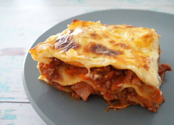 A serving of a Thermomix Mince Recipe, Lasagna with a cheesy top, on a blue plate