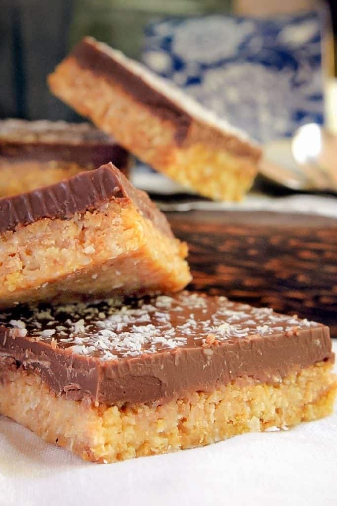 A close up of Chocolate and Coconut Slices stacked on top of one another. 