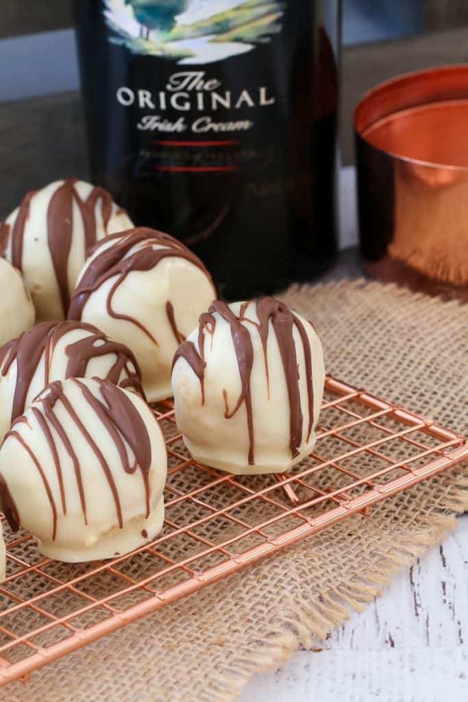 White chocolate balls drizzled with milk chocolate on a copper wire tray