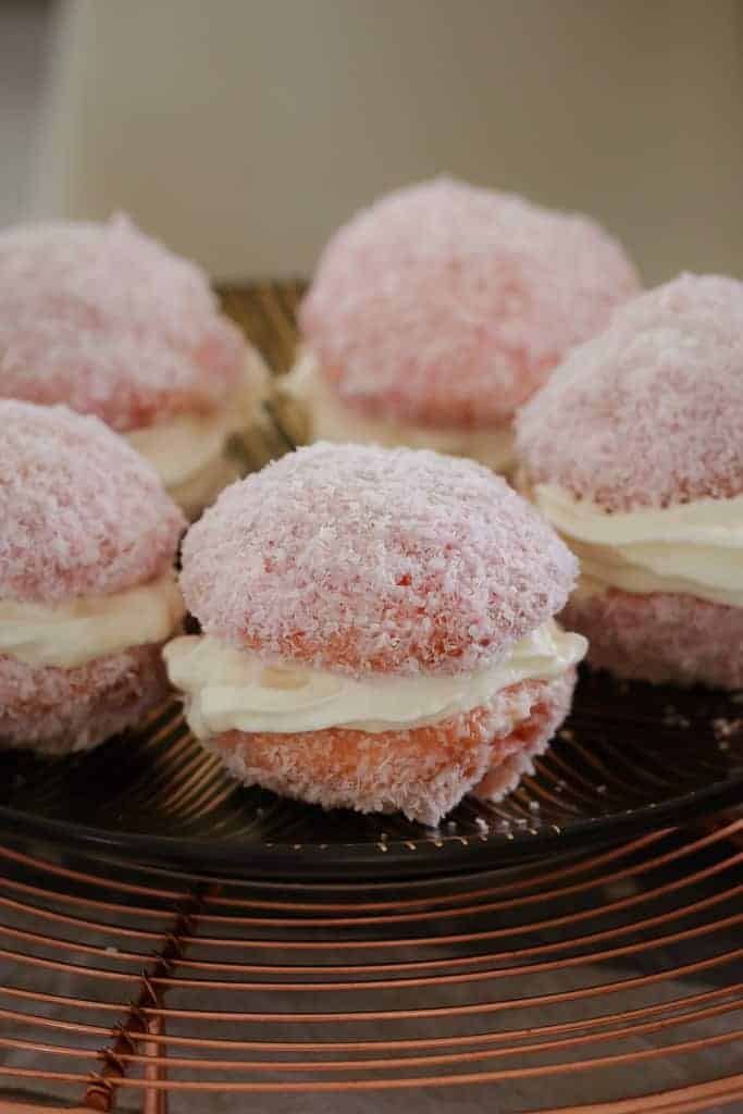 A plate of raspberry jelly cakes coated in coconut. 