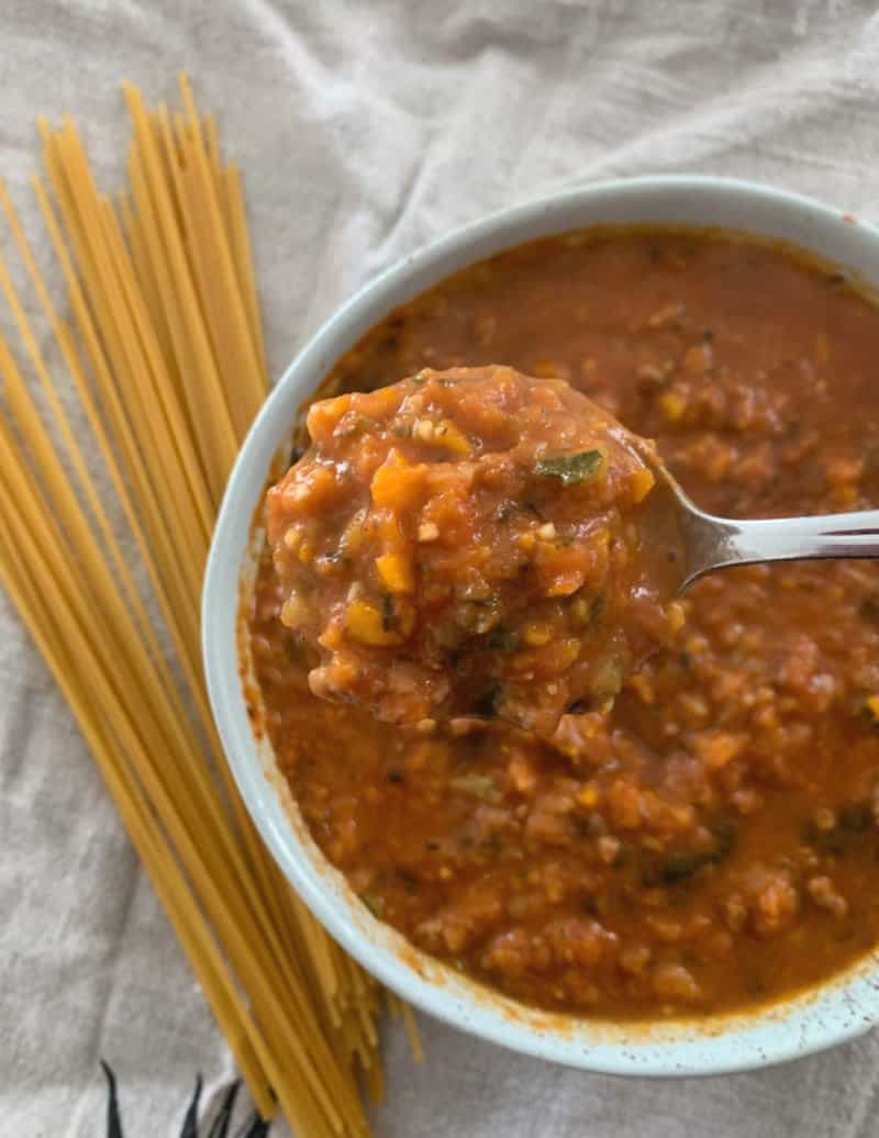 A spoon in a bowl of chunky bolognese sauce