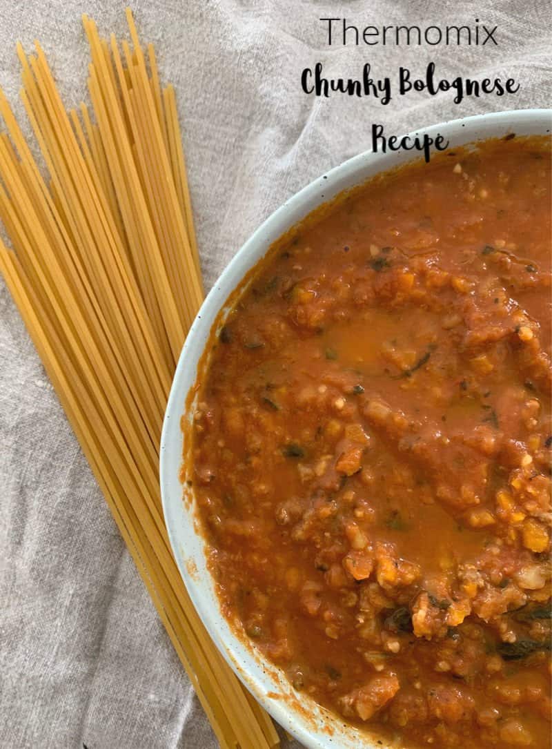 A bowl of bolognese sauce with a handful of  dry spaghetti beside