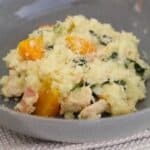 A bowl of risotto with pumpkin, chicken, bacon and spinach.