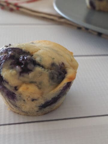 A close up of a baked muffin with lots of blueberries mixed through it.