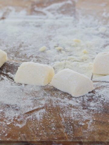 Homemade gnocchi on a floured wooden board.