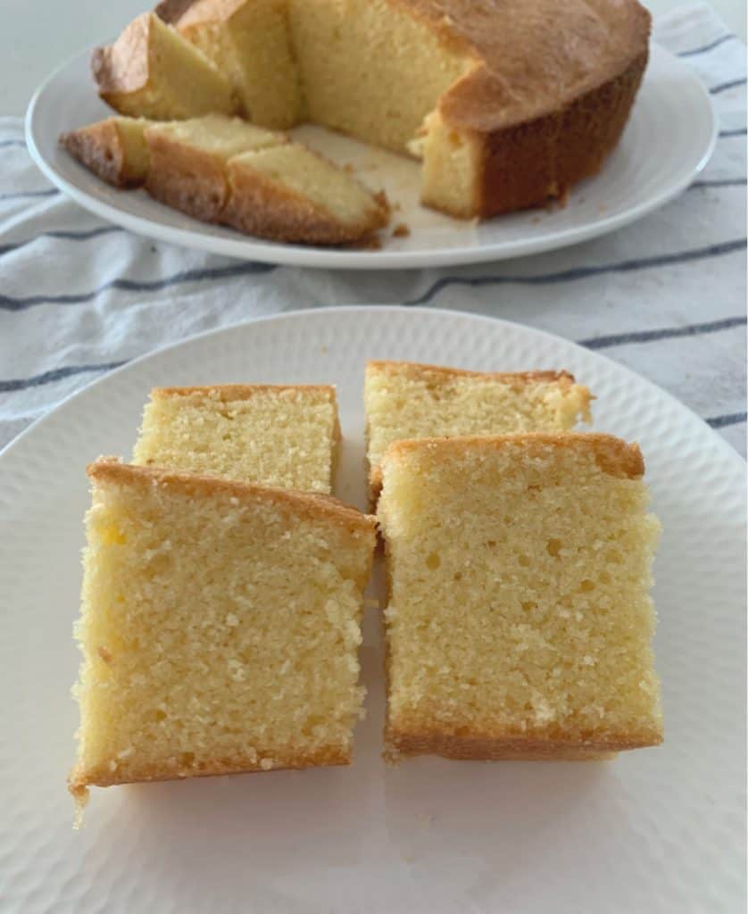 A white plate with four pieces of a plain pound cake served on it.