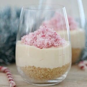 A tall glass with biscuit base, cheesecake and chopped candy cane on top.