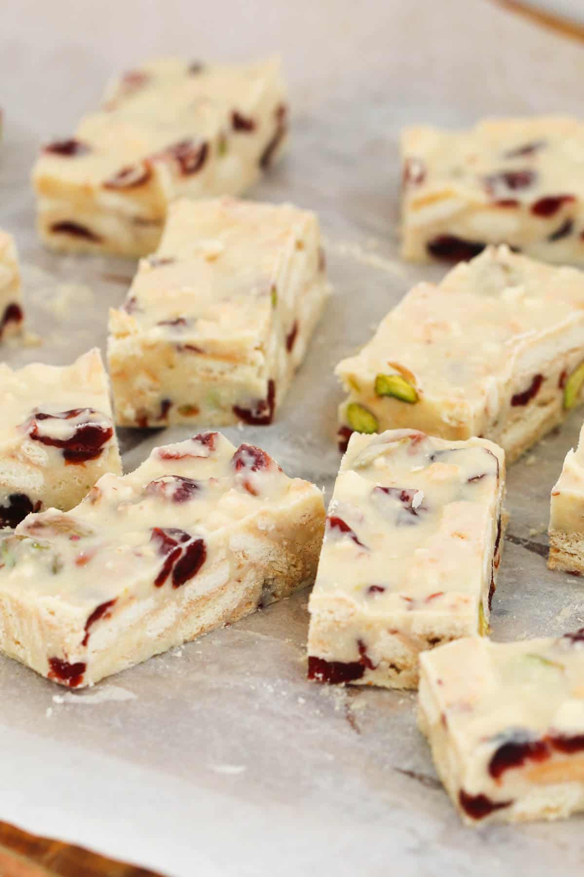 Pieces of white chocolate, pistachio and cranberry slice on baking paper.