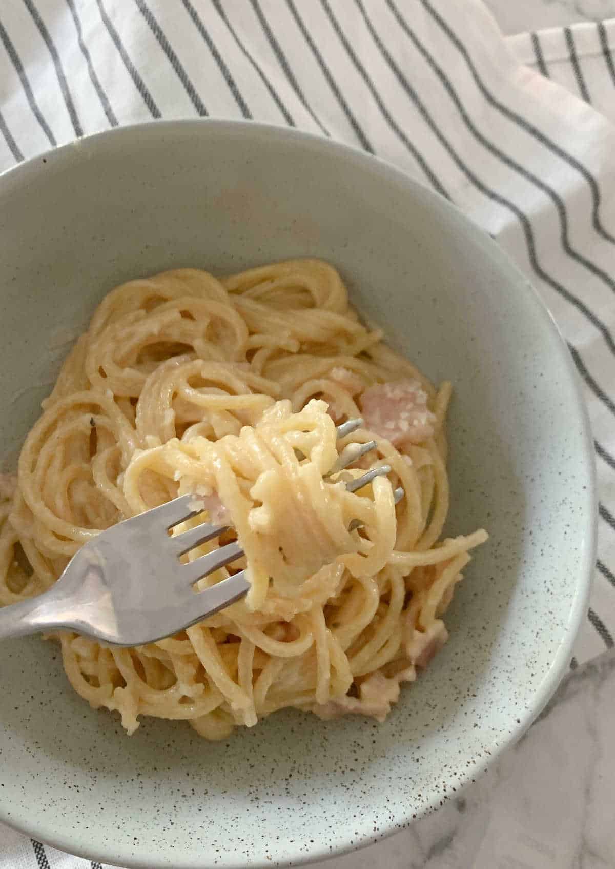carbonara on a fork above a bowl