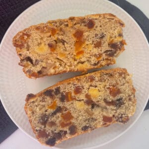 Overhead view of Two slices of Fruit Loaf made in a thermomix on a white plate.