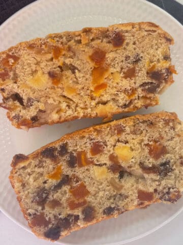 Overhead view of Two slices of Fruit Loaf made in a thermomix on a white plate.