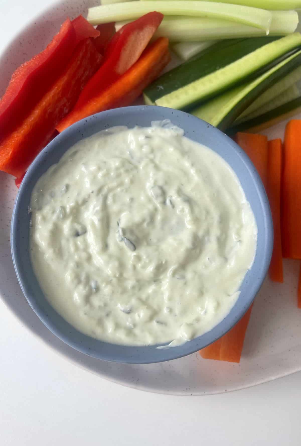 Tzatziki Dip in a blue serving bowl surrounded by veggie sticks.