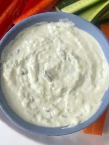 Tzatziki Dip in a blue serving bowl surrounded by veggie sticks.