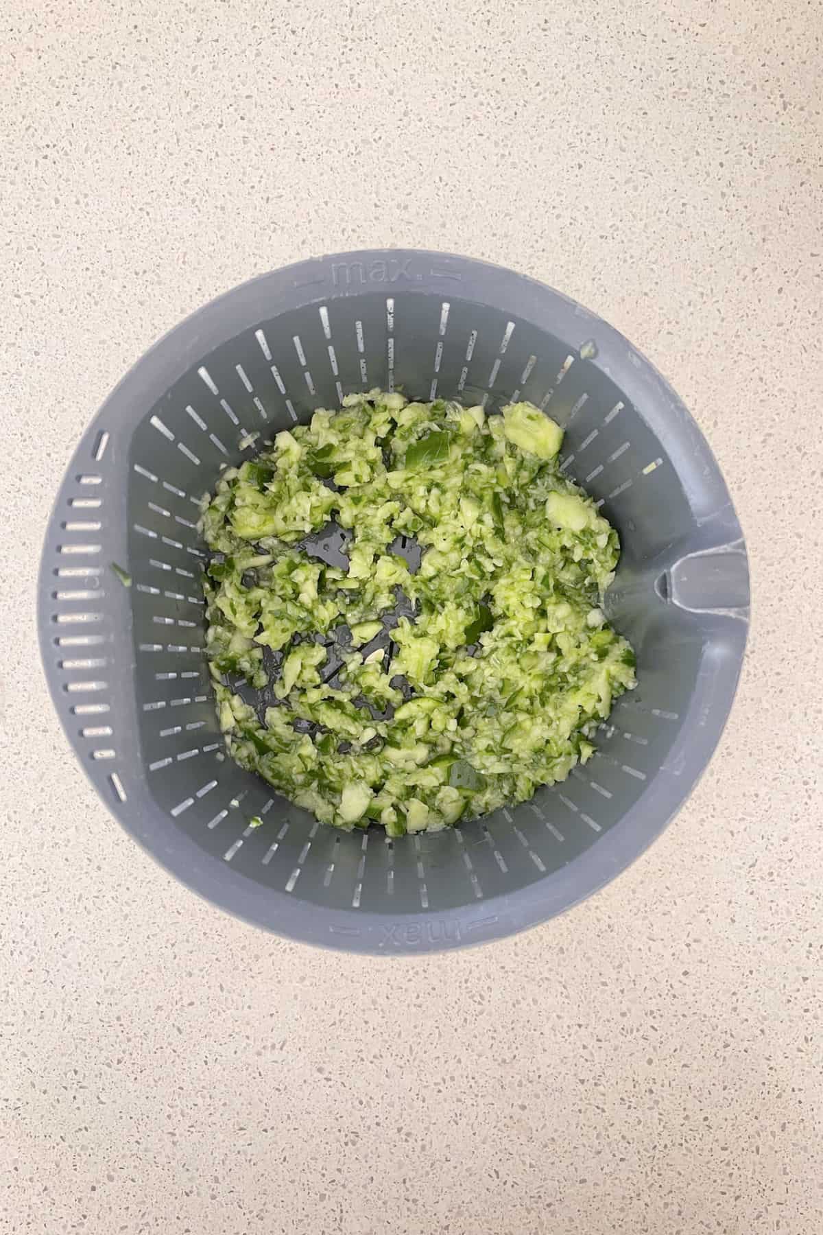 Cucumber pieces draining in a thermomix basket.