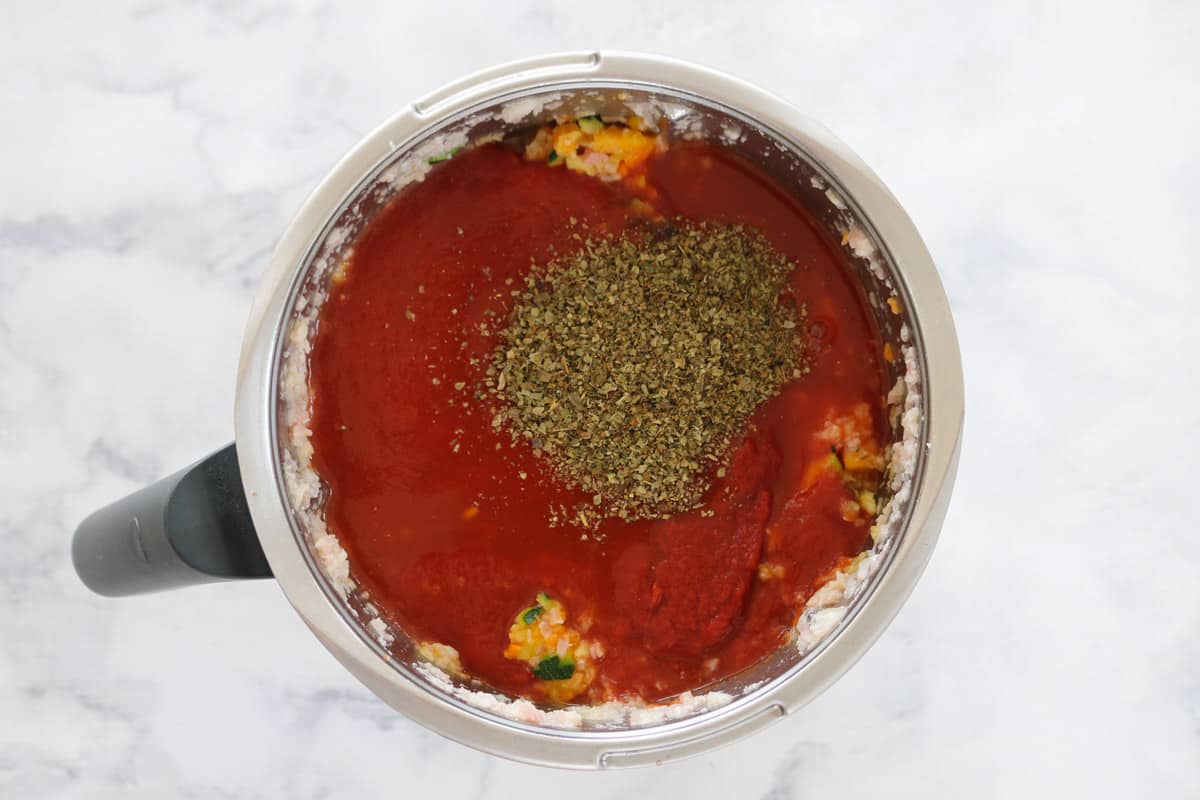 Tomato sauce and tomatoes and herbs in a Thermomix bowl. 