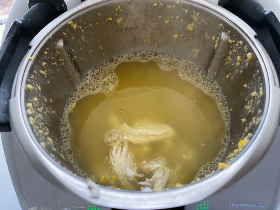 Chicken stock liquid and shredded chicken in a Thermomix.