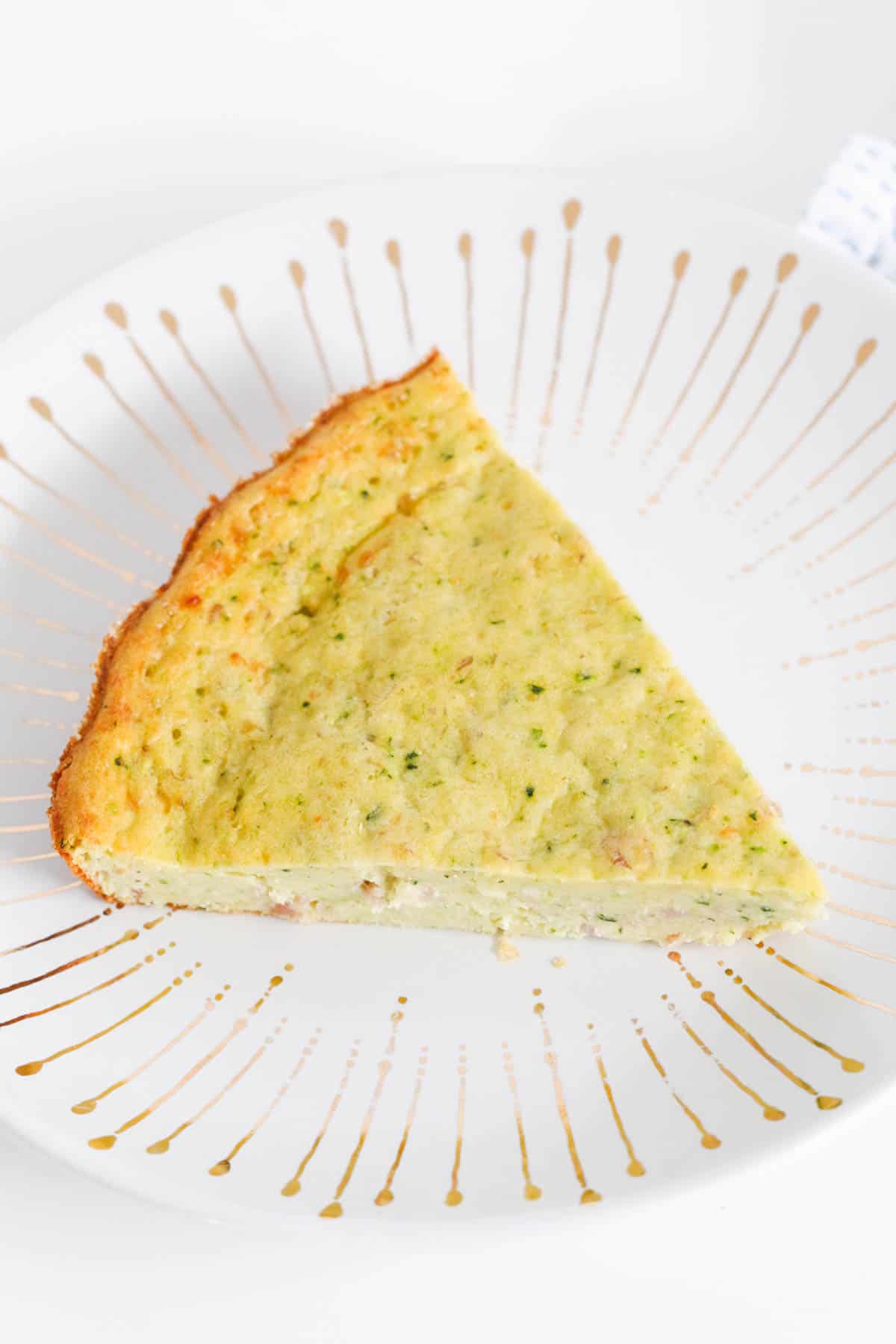 A triangular piece of zucchini slice on a plate.