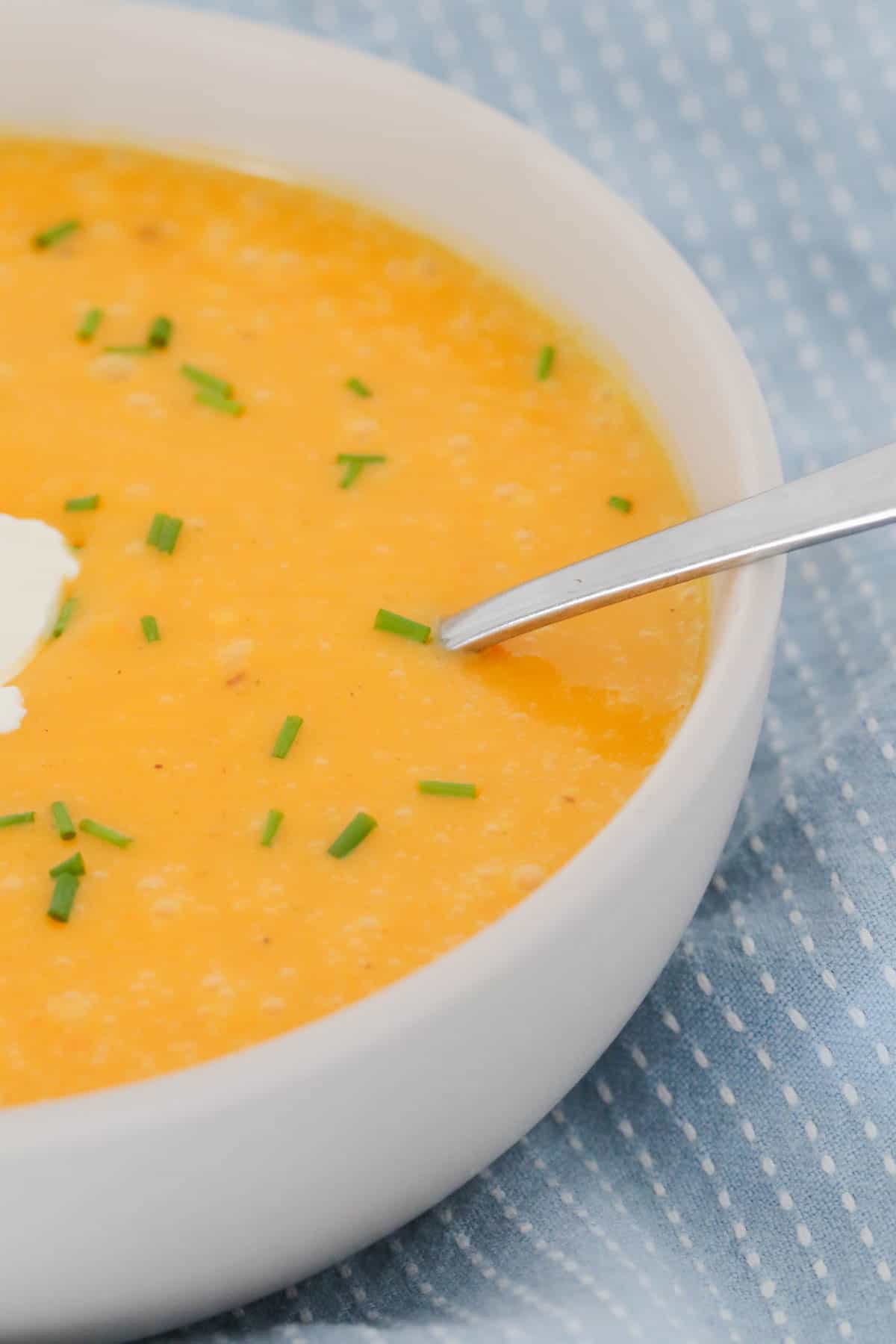 A bowl of pumpkin soup topped with sour cream and chives.