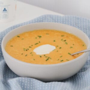 A spoon in a bowl of pumpkin soup made in a Thermomix.