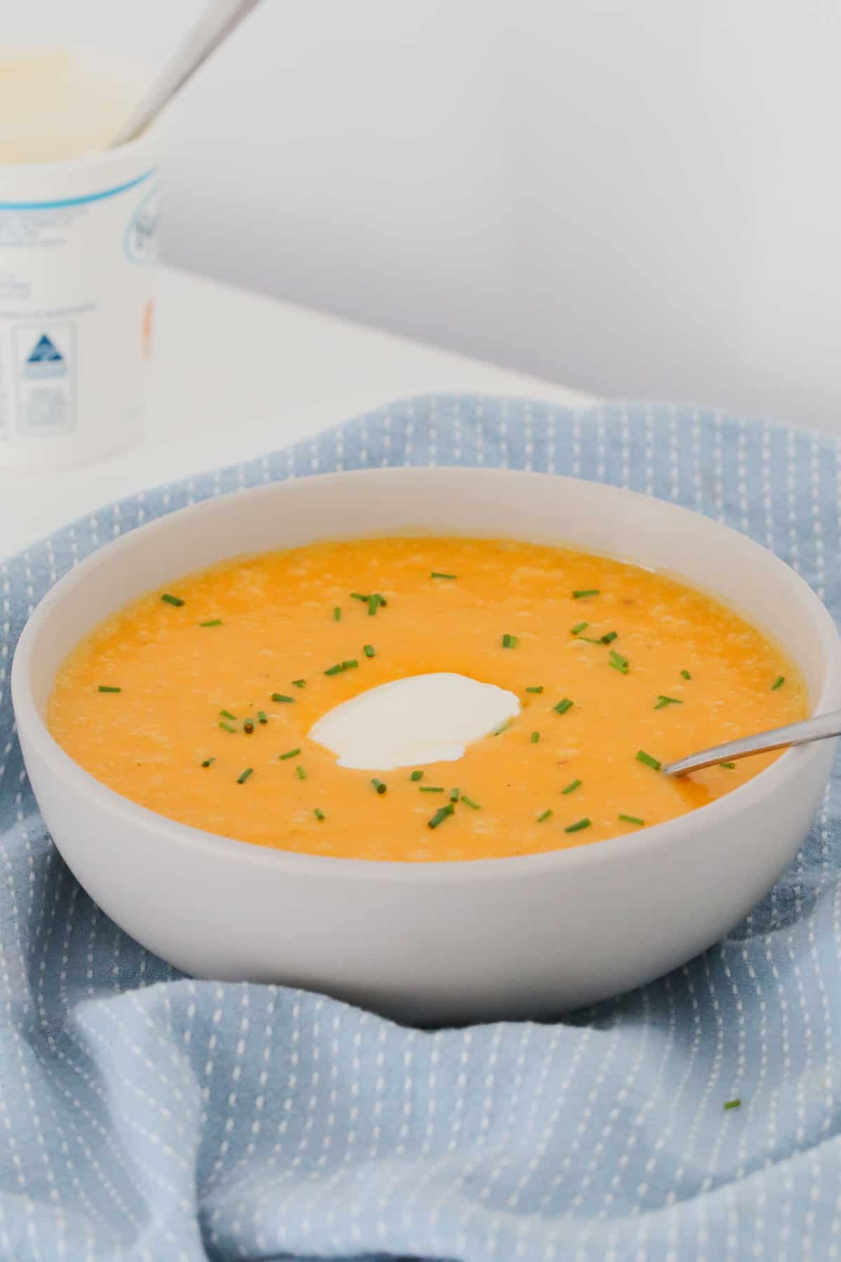 A spoon in a bowl of pumpkin soup made in a Thermomix.
