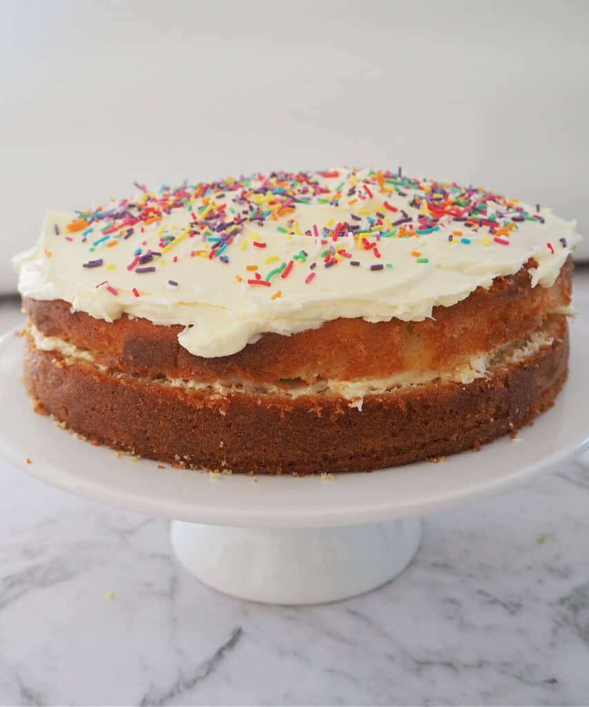 Butter cake with white buttercream on white cake stand