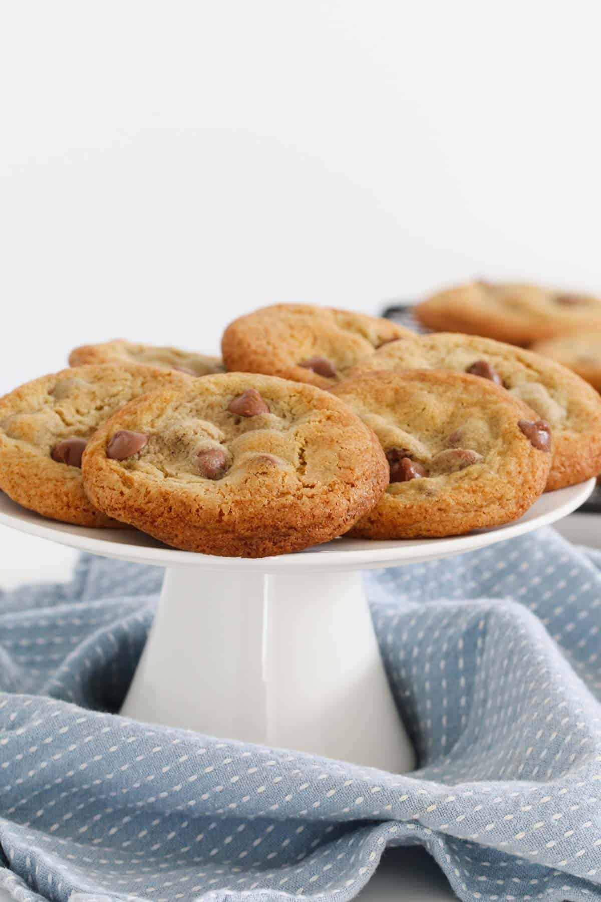 A white cake stand topped with chocolate chip biscuits.
